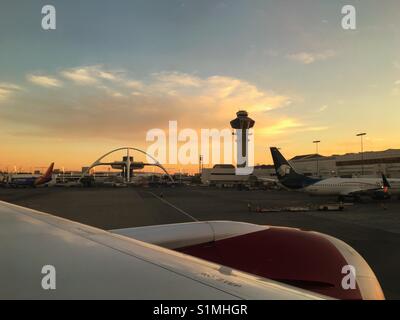 Marzo 2017 - spingendo indietro dal terminale di discostarsi dall'aeroporto di Los Angeles al tramonto con sagome di l'aeroporto la struttura iconica e la torre di controllo Foto Stock