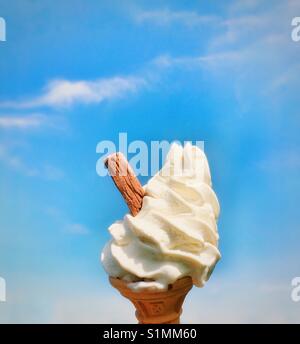 Cono gelato con panna gelati e scaglie di cioccolato contro un cielo blu Foto Stock