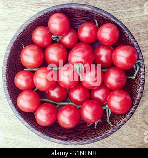 Ciliegia di colore rosso dei pomodori in una ciotola di legno Foto Stock
