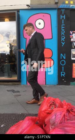 L'uomo passando da un murale di street artista Thierry Noir in Shoreditch London REGNO UNITO Foto Stock