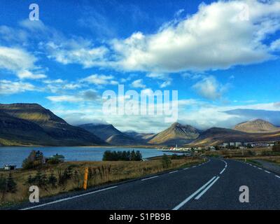 Vista montagna dall'auto. sulla strada, guidando attraverso una piccola città in Islanda Foto Stock