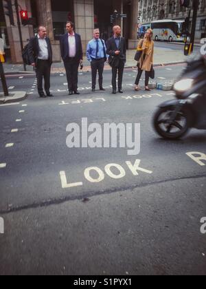 Pedoni attendere di attraversare una strada trafficata nel centro di Londra, Inghilterra Foto Stock