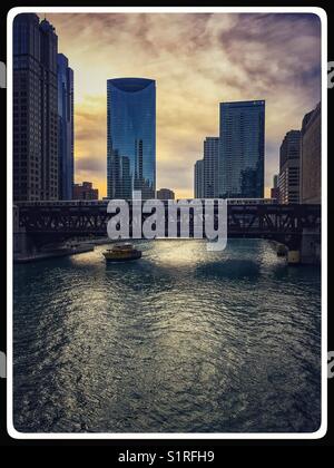 Splendida vista sul fiume di Chicago come il sole inizia la discesa e taxi d'acqua scompare sotto un ponte. Foto Stock