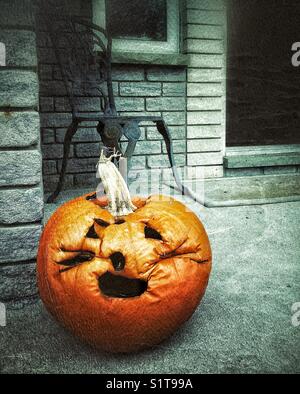 Zucca di Halloween (jack-o-lantern) marciume sulla casa porte settimane dopo halloween Foto Stock