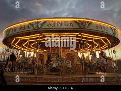 Tutto il divertimento della fiera. Giostra a Lee Valley White Water Centre Mercatino di Natale. Subito dopo il tramonto con nuvole grigie e un tocco di oro. Foto Stock