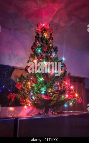 Un piccolo albero di Natale illuminato sopra un frigorifero Foto Stock