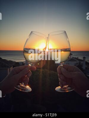 Due bicchieri tintinnanti al tramonto. saluti! Foto Stock