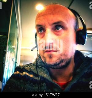 Ritratto di un uomo che indossa una cuffia in un ambiente di ufficio. Foto Stock