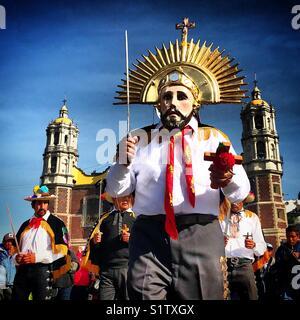 Un danzante di indossare una maschera e una corona detiene una spada e una croce durante l'annuale pellegrinaggio alla Madonna della basilica di Guadalupe a Città del Messico Foto Stock