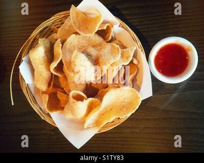 Un cestello di cracker ai gamberi con una ciotola di salsa al peperoncino dolce. Foto Stock