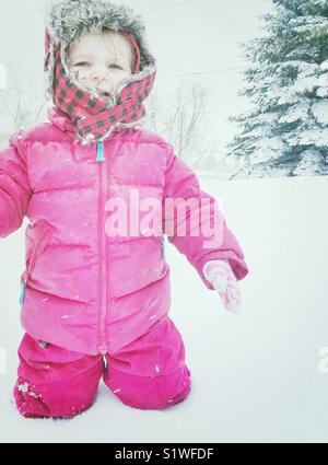 Il Toddler girl in piedi nella neve profonda preinstallato in doposci piangere Foto Stock