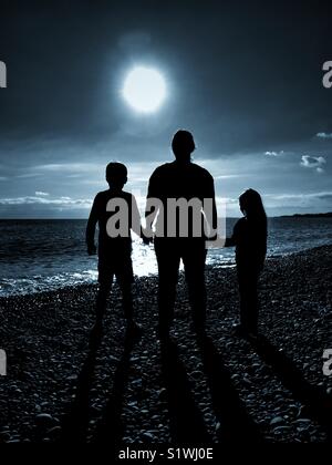 Le sagome di 3 persone - una madre tiene le mani dei suoi 2 figli come essi tutti guardare avanti verso una luce brillante. Un'immagine che illustra le questioni sociali e ha molteplici usi. © COLIN HOSKINS Foto Stock
