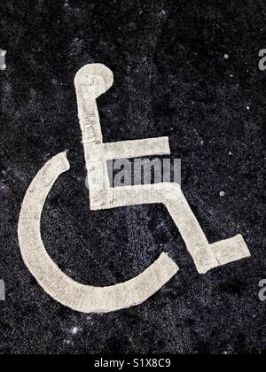 Un parcheggio disabili simbolo dipinto sul pavimento in un parcheggio. Foto Stock