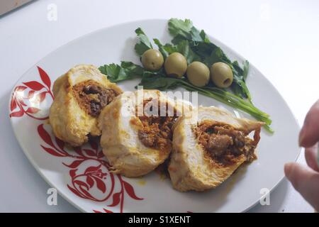 Preparazione di carni macinate rotoli. Come un ripieno di uova sode. Fette di rotolo finito sono su una piastra con olive nere e verdi. Foto Stock