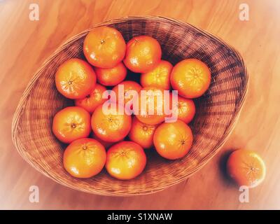 Mandarini arance in un cesto su un tavolo di legno, ad alto angolo di visione Foto Stock