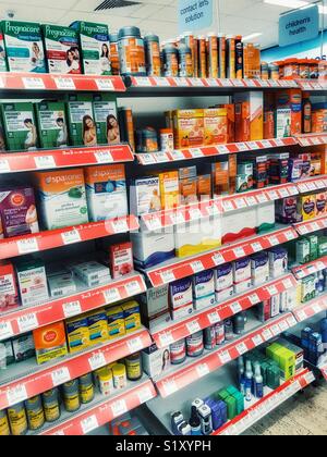 Avvia il farmacista, interno, ben rifornita ripiani con una varietà di farmaci OTC Foto Stock