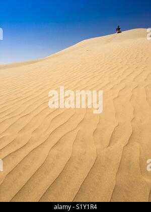 Tourist seduti sulla cima di una duna di sabbia in Rub Al-Khali, (Empty Quarter) deserto in Dhofar, Oman. Foto Stock