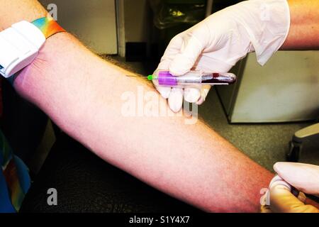 Una pratica infermiere prende un campione di sangue dal braccio di un uomo di mezza età come parte di un NHS health check test. Regno Unito Foto Stock