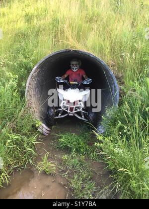 Equitazione ATV attraverso una tubazione di tempesta Foto Stock