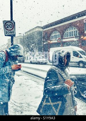 Scena di strada e persone che lottano attraverso forti nevicate in London, N7 durante la tempesta da est blizzard nel marzo 2018. Foto Stock