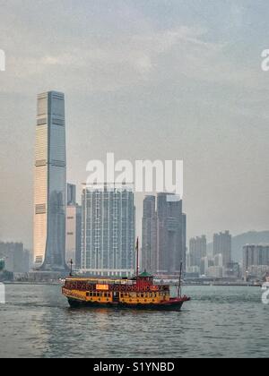 Il 'ala su Travel', un double decker giunca Cinese, portando i turisti in una crociera turistica sul Victoria Harbour al crepuscolo, di fronte alla Corte penale internazionale, Hong Kong grattacielo più alto del, nel West Kowloon Foto Stock