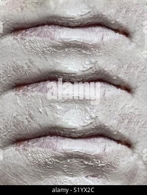 Un immagine astratta di tre set di labbra, su una faccia che indossa una argilla bianca maschera di fango