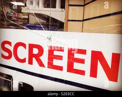 Incrinature del negozio finestra in un telefono mobile shop che le riparazioni incrinato nelle schermate del dispositivo Foto Stock