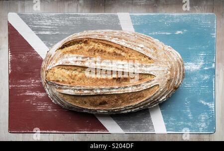 Pane appena sfornato sourdough pagnotta di pane visto dal di sopra su angosciate di legno verniciato board Foto Stock