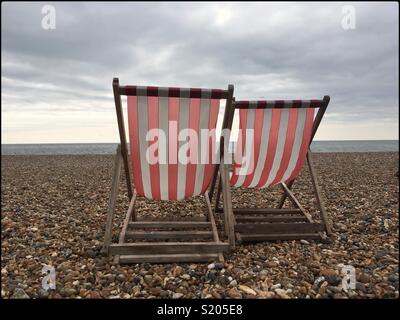 Due a strisce rosse e bianche sedie a sdraio sulla spiaggia di Brighton, Inghilterra, Aprile 2018 Foto Stock