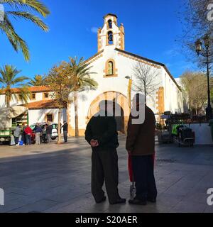 Silhouette di vecchi uomini che parlano in una piazza nei giorni di mercato, nella Città Vecchia di Javea sulla Costa Blanca, Spagna Foto Stock