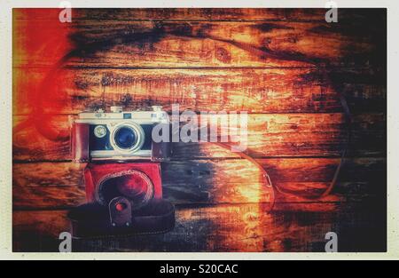 Lay piatto foto di una fotocamera vintage con la sua custodia in pelle su un grungy tavolo in legno. Foto Stock
