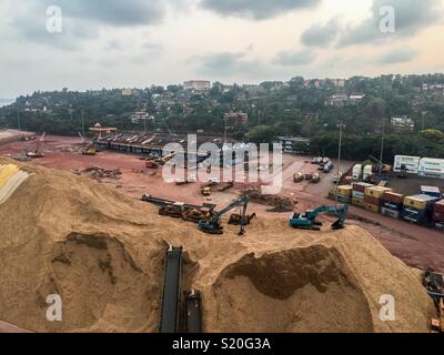 Escavatrice stanno elaborando i trucioli di legno nel porto di Goa, India Foto Stock