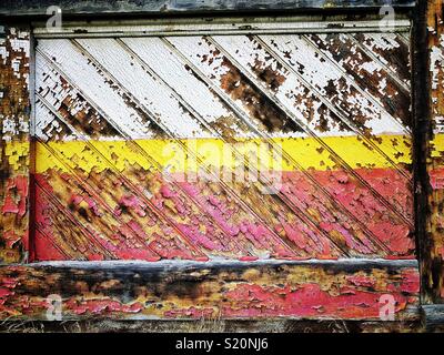 Il bianco, il rosso e il giallo di pelatura su vernice vecchia parete in legno in antilopi, Oregon Foto Stock