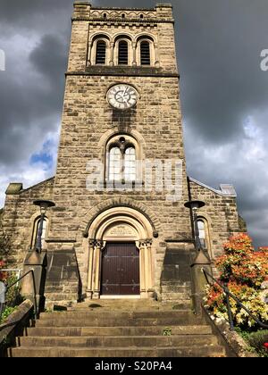 Sole illuminava il campanile della chiesa di San Giovanni a Ashbourne contro un buio cielo tempestoso Foto Stock