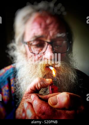 Uomo anziano accendere una sigaretta Foto Stock