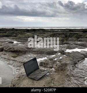 Laptop scartato sulla spiaggia Foto Stock