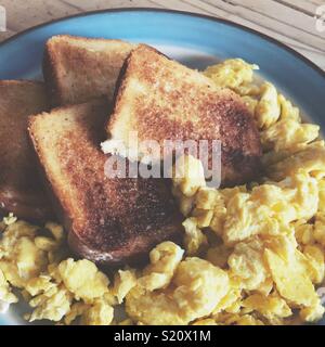 Primo piano di uova strapazzate e pane tostato su una piastra Foto Stock