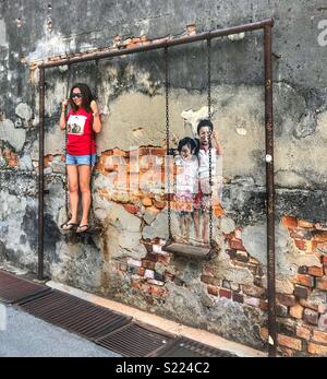 Turista femminile interagisce con whimsical di arte di strada nella storica Georgetown, Penang. Foto Stock