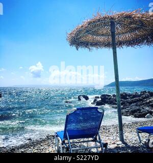 Lettino e ombrellone sulla spiaggia di Kardamyli, Grecia con il blu del cielo e del mare Foto Stock