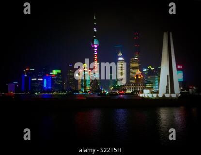 Shanghai di notte con una barca a vela passando sul fiume Bund Foto Stock