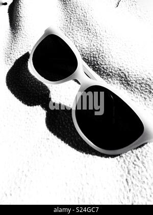 Immagine in bianco e nero di occhiali da sole su una coperta Foto Stock
