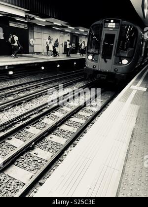 La District line tubo tirando in Victoria station platform Foto Stock