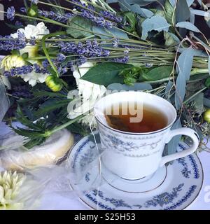 La foto di un luogo di matrimonio impostazione compresa una British tazza da caffè con piattino, bouquet nuziale, e cookie bianco Foto Stock