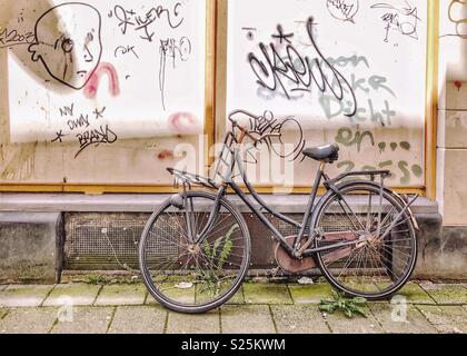 Vecchia bicicletta puntellato contro un muro di graffiti in Olanda, 2018 Foto Stock