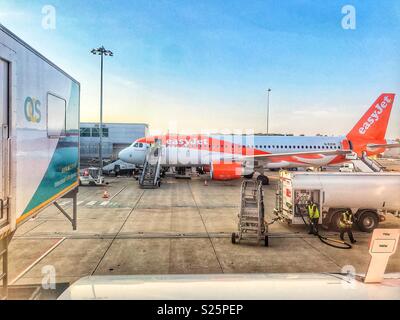 Guardando fuori della finestra da un aereo EasyJet con un sollevamento di ambi essendo rifornito, a un altro aereo EasyJet in attesa sull'asfalto, l'aeroporto di Bristol, Inghilterra Foto Stock
