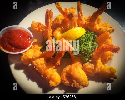 Golden gamberi fritti con limone e salsa cocktail, vignette filtro applicato Foto Stock