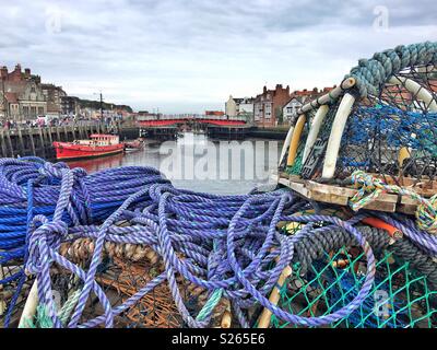 Il porto e il ponte sul fiume Esk a Whitby, North Yorkshire, Inghilterra, con pentole di granchio, funi e reti da pesca Foto Stock