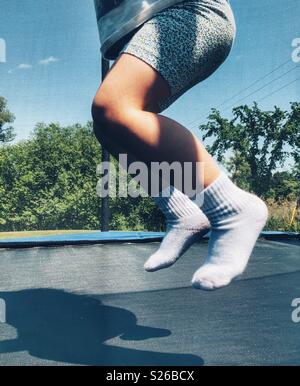 Il Toddler girl gambe e piedi in aria saltando su un trampolino Foto Stock