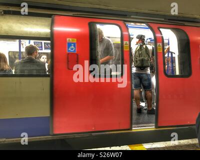 La metropolitana di Londra, le persone in una regione del nord della linea ferroviaria metropolitana, porte aperte, la stazione della metropolitana di Leicester Square, Londra, Inghilterra Foto Stock