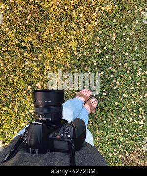 Punto di vista immagine della persona in piedi nella patch di trifoglio con Nikon reflex fotocamera Foto Stock